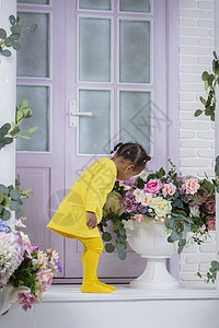 穿黄色洋装的非洲小女孩 在紫色门附近闻到一束花图片