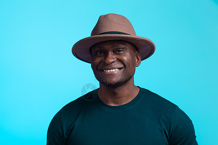 笑笑快乐的美国非洲男人 在蓝背景上戴着时尚帽子 喜剧和政党概念图片