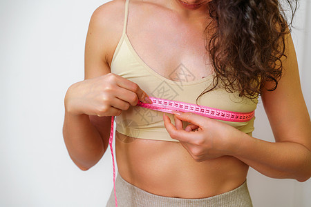 在家里用卷尺测量乳房的苗条女人的剪影 特写 面目全非的欧洲女性在室内检查减肥饮食或抽脂的结果 健康的生活方式营养裁剪磁带损失健身图片