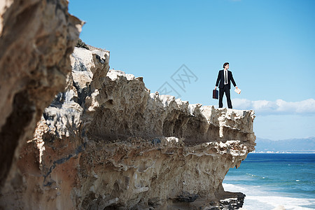 商务人士站在悬崖的边缘看着海洋 拿着公文包 (掌声 贾斯丁先生在看望着大海)图片