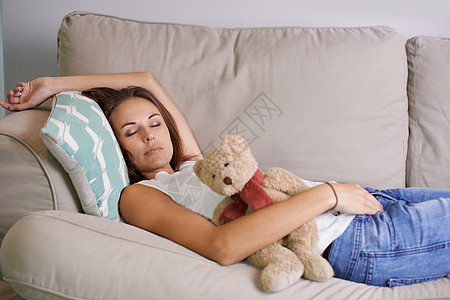 即使妈妈有时也需要睡午觉 年幼的妈妈在沙发上快睡着 带着孩子Teddy熊女性女士长椅母亲成人孩子们睡眠休闲服啤酒婴儿图片