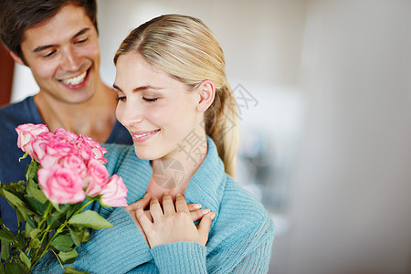 给一个可爱的年轻男人给他美丽的年轻妻子一束粉红玫瑰花 被射中了 (笑声)图片