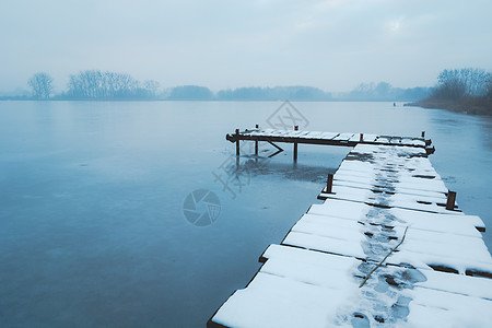 冰冻湖上一个雪覆盖的木头码头图片