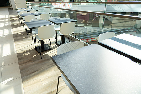 为现代购物中心食品法院的来访者提供一排配白椅子的桌椅表购物中心公司桌子用餐法庭店铺商业咖啡食物中心图片