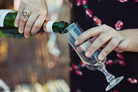 香槟在聚会上总是一个好主意 在外面的茶话会上 一位面目全非的女士将香槟倒入玻璃杯中的特写镜头图片
