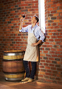 成熟的红酒制造者在他的地窖里喝着一杯红葡萄酒 他从不喝酒图片