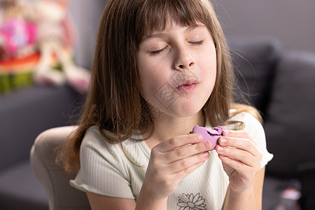 家庭背景的女学生舔着嘴唇 吃着一个紫罗兰色的马卡龙 高兴地闭上了眼睛 甜点人 爱吃甜食 美食家 感觉不错 好吃图片