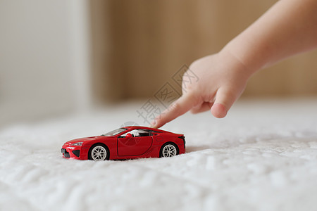 孩子手玩玩具车的特写镜头 白色背景中推着塑料玩具车的小孩的手游戏驾驶汽车幼儿园车辆学习婴儿孩子们活动娱乐背景图片