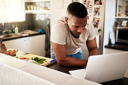 我们来看看一些新的食谱 一个英俊的年轻人在家中厨房做早餐时 使用数字平板电脑拍到的一张照片图片