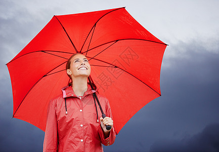 我被保护不受天气的影响 一个美丽的年轻女人站在外边 拿着她的红伞站着图片
