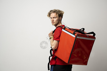 Cocnept快递服务公司 穿红色制服的Couier和热背包袋 看白色工作室背景上孤立的相机小样商业盒子员工运输邮递员店铺信使背图片