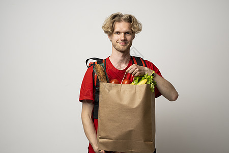 男人拿着纸袋 里面装着白色背景的杂货店的新鲜产品 送餐服务市场男性展示衬衫导游工作蔬菜购物成人食物图片