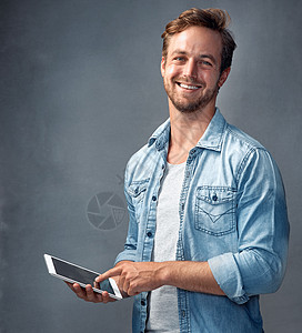 他是谁一个英俊的年轻人用平板电脑 在工作室里使用灰色背景的肖像 照片显示他是个年轻帅哥背景