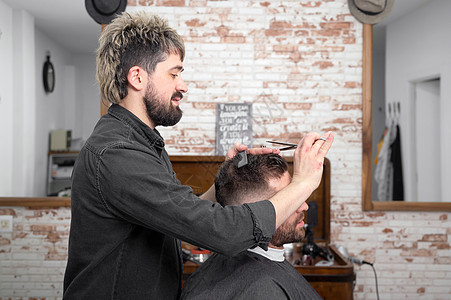 理发师用剪刀剪头发给一个英俊的年轻人造型师发型师椅子理发服务发型成人职业摄影店铺图片