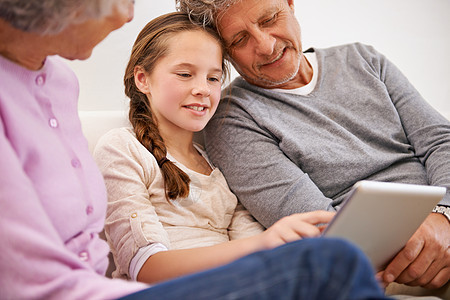 这就是社交媒体的世界 祖父母看着他们的孙女使用数字平板电脑的镜头图片