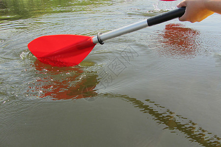 白流水和皮划艇的红桨 在河上紧贴一只红手 有滑板或木筏 还有春季水运动的概念 选择性焦点图片