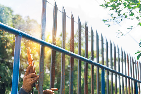特写拉丁美洲一名蓝领工人的手 不安全地焊接金属栅栏和将铁丝网焊接建造红色生产男人维修男性焊机工具劳动工作图片