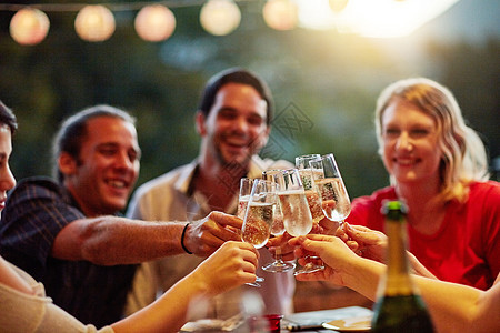 一群快乐的年轻朋友在后院晚宴派对上用香槟敬酒 被拍到的照片 (笑声 “我们为庆祝而欢呼”)图片