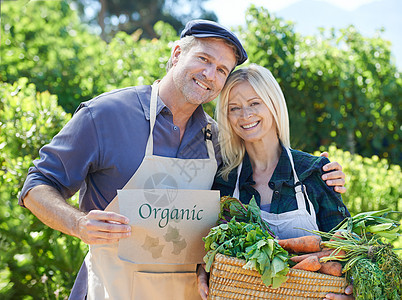一个成熟的农夫夫妇 拿着一篮新鲜采摘的蔬菜吃着图片