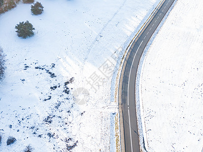 穿过白雪覆盖的冬季森林的浪漫之路的鸟瞰图 俯瞰松树的顶端 中间是一条黑色的柏油路天空木头公园季节场景天线白色太阳图片