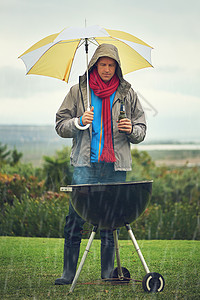 真正的男人随时随地都在吹嘘 一个男人在雨中烤肉的镜头图片