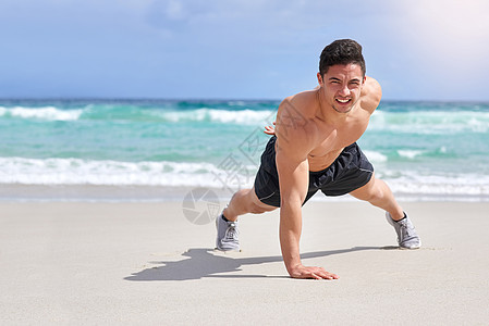 一个英俊的年轻人在沙滩上做一个俯卧撑 长得像个大帅哥图片