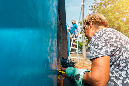 从事户外工作的活跃的拉丁美洲老年妇女在她家墙壁上涂漆图片