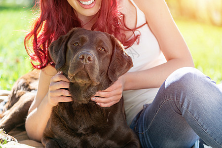 年轻女人和她的狗在公园里乐趣女性黑色皮带中年动物喜悦宠物成人猎犬图片