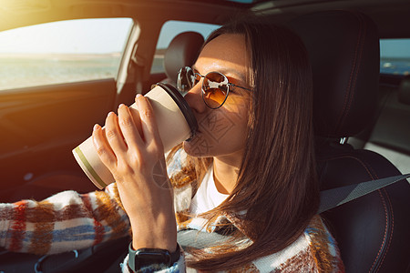 年轻美丽的女士开车喝咖啡 并驾车图片