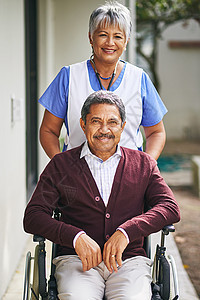 一位坐在轮椅上的老人的肖像在养老院由一名护士照顾 而他却带着笑容向人们伸出援手图片