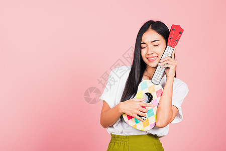 女青少年自信的笑脸 握着音响Ukulele吉他细绳音乐家音乐喜悦尤克里里歌曲歌手乐趣幸福女性图片