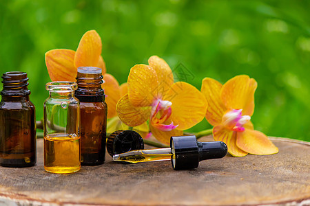 用黄色兰花和天然油 来按摩石油和石头身体疗法香气植物群卵石玻璃液体药品香水瓶子图片