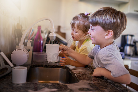 完成后它们会非常干净 两个可爱的小兄弟姐妹在家里的厨房里一起洗碗的镜头图片
