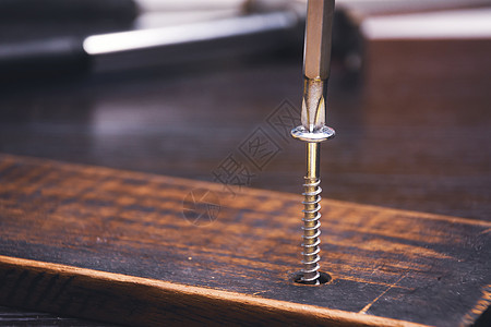 木制木匠是铁链螺栓 十字螺丝起子在木板上的硬木板上图片