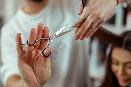 近身的理发师手紧紧握着头发线 同时剪裁女性客户的头发图片