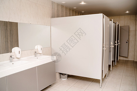 公共厕所的内部 一排用大理石板上金属水龙头的洗浴盆 液体肥皂施放器 灰墙上的长镜子图片