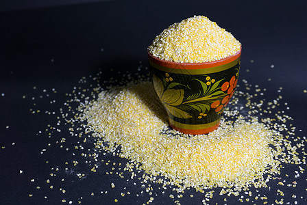黑色背景的木碗里生黄黄色玉米粉面粉图片