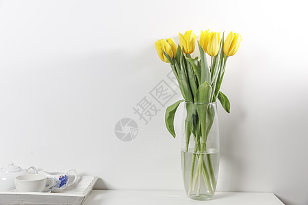 白色桌上玻璃花瓶中的黄色郁金香布叶子花园女性季节广告牌海报妈妈框架女士广告图片
