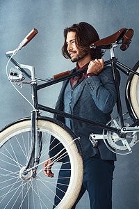 演播室拍到一个时髦的英俊帅哥 在灰色背景下骑着脚踏车 他穿着自行车图片