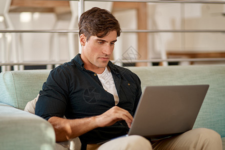 有了互联网 您总能在正确的时间出现在正确的地点 一名男子在家里的沙发上放松时使用他的笔记本电脑的裁剪镜头图片