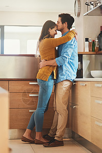 被一个可爱的年轻男人在厨房前额上亲吻女友的照片拍下来了 她的脸部和她的女朋友擦肩而过图片