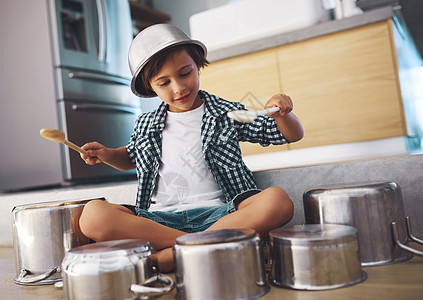释放史诗般的鼓独奏 一个快乐的小男孩头上戴着碗 在厨房地板上用罐子打鼓的镜头图片