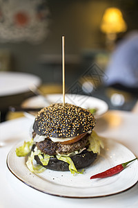 黑色面粉汉堡 在盘子上加红辣椒烹饪牛肉烧烤美食美味芝麻食物洋葱辣椒午餐图片