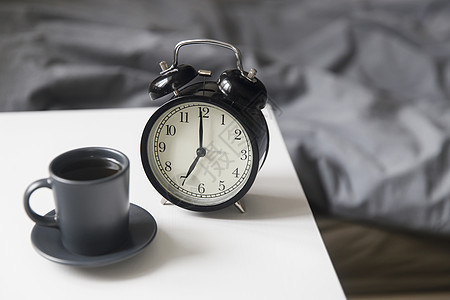 一张黑色咖啡杯的图像闹钟在床前白床边桌子上 上面有灰色麻布 房间在米色调中寝具警报早餐窗户咖啡杯子活力女性时间卧室背景图片