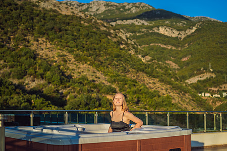 在绿色大山的背景下享受快乐旅行时刻假期生活的年轻无忧无虑的快乐微笑女人在热水浴缸中放松的肖像漩涡液体成人奢华酒店蓝色天空闲暇女性图片
