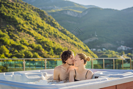 在绿色大山的背景下 享受快乐旅行时光假期生活的年轻无忧无虑的快乐微笑夫妇在热水浴缸中放松的肖像按摩关系生日泳池温泉卫生蒸汽纪念日图片