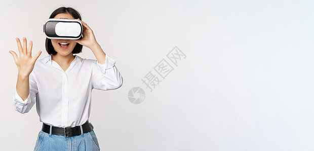虚拟聊天 亚洲女孩戴着虚拟现实眼镜打招呼 热情微笑 沟通概念和未来技术 白色背景人士女士女性冒充手臂标识企业家商务管理人员成人图片
