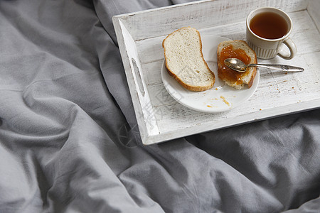 茶壶 茶杯 两片烤面包和杏仁果酱放在床头桌子上的盘子上图片