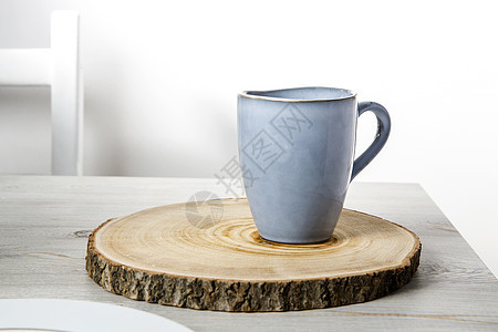 一个蓝色陶瓷杯 用木制圆形的铜杯在米色桌子上对面白色墙壁切开 文本的位置 复制空格图片