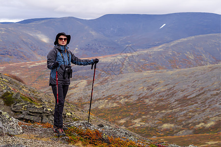 青年女山区旅游者 在山地背景上戴着带高柱的眼镜背包爬坡远足女孩悬崖石头踪迹顶峰女性男人图片